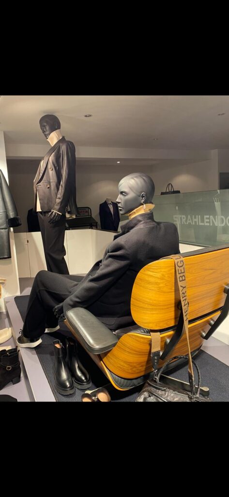 Designer-Anzüge im Schaufenster von Strahlendorff Hamburg Schaufenster der Strahlendorff Boutique Hamburg mit Mannequins in stilvollen Designer-Anzügen, eines sitzend auf einem Leder sessel.